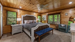 Une chambre dans une cabane en bois, comprenant un lit, une commode, un banc et deux chaises.