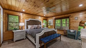 A wooden cabin bedroom with a bed, dresser, bench, and two chairs.