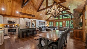 Une cuisine spacieuse dotée de meubles en bois, d’un grand îlot central et d’un coin repas avec une table et des chaises en bois.