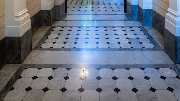 Un couloir avec un sol à motifs et des murs blancs.