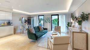 A modern living room with a green sofa, a dining area, and a kitchen. - Spa Du Cap 2 bedroom apartment (Antibes)