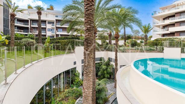 A modern hotel with a pool, palm trees, and a curved walkway. - Spa Du Cap 2 bedroom apartment (Antibes)