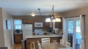Una cocina moderna con armarios de madera, una isla central y un comedor con mesa y sillas.
