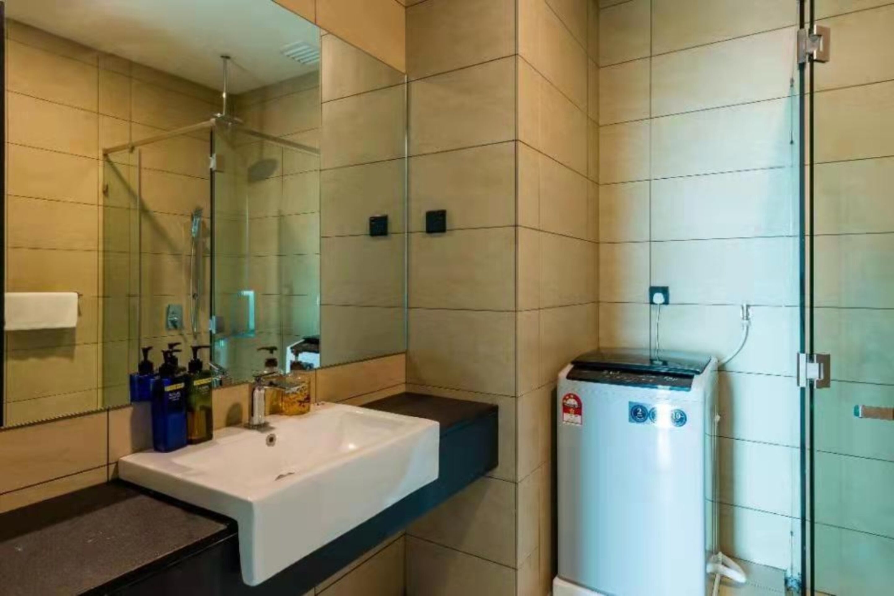 A modern bathroom with a large mirror, a white sink, and a water heater.