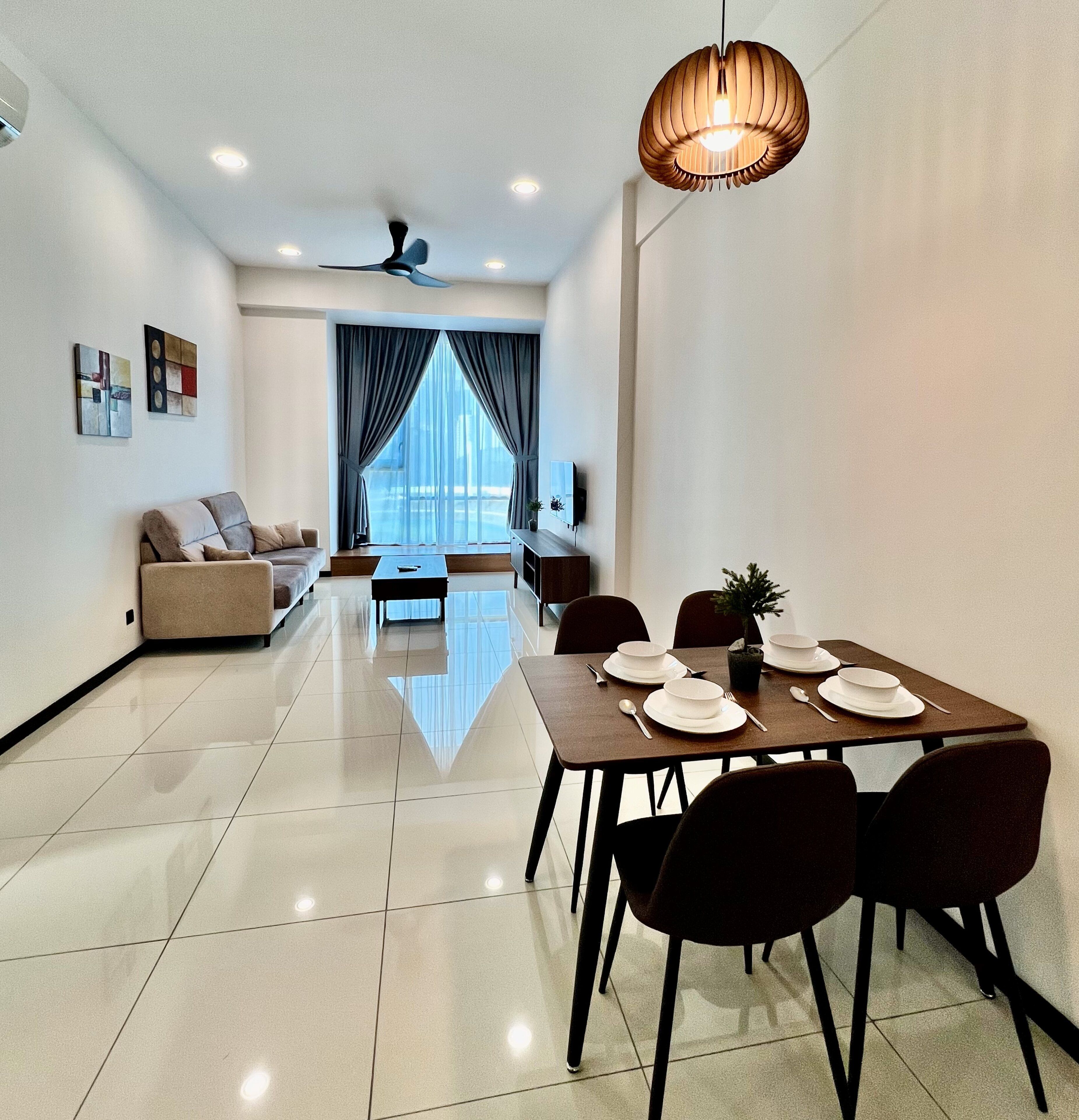A modern living room with a sofa, a dining table set for four, and a ceiling fan.