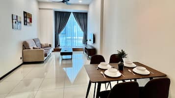 A modern living room with a sofa, a dining table set for four, and a ceiling fan.