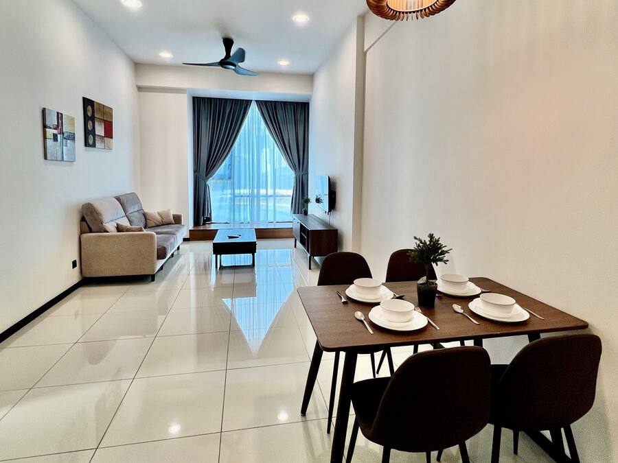 A modern living room with a sofa, a dining table set for four, and a ceiling fan.