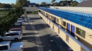 A hotel with a covered outdoor area, a parking lot, and a building with a blue roof. - Star Inn Motel (Costa Mesa)