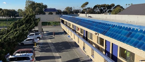 Un hotel con un área exterior techada, estacionamiento y un edificio de techo azul.