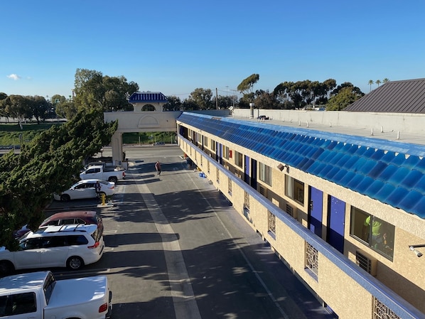 Un hotel con un área exterior techada, estacionamiento y un edificio de techo azul.