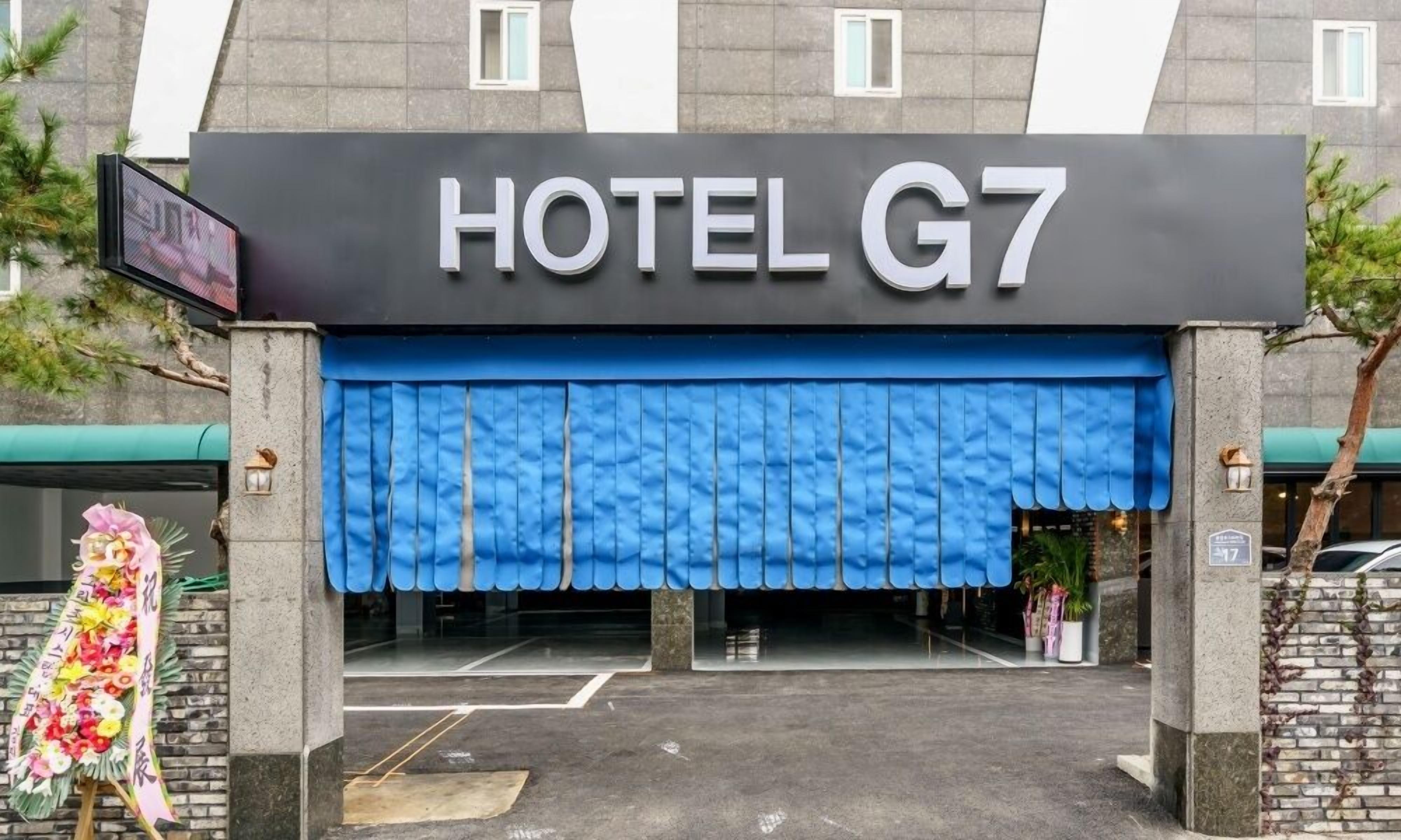 La entrada del HOTEL G7, con un toldo azul y un letrero sobre la entrada.
