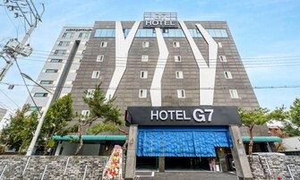 Un moderno edificio de hotel con un llamativo letrero de 'HOTEL G7' en la entrada.