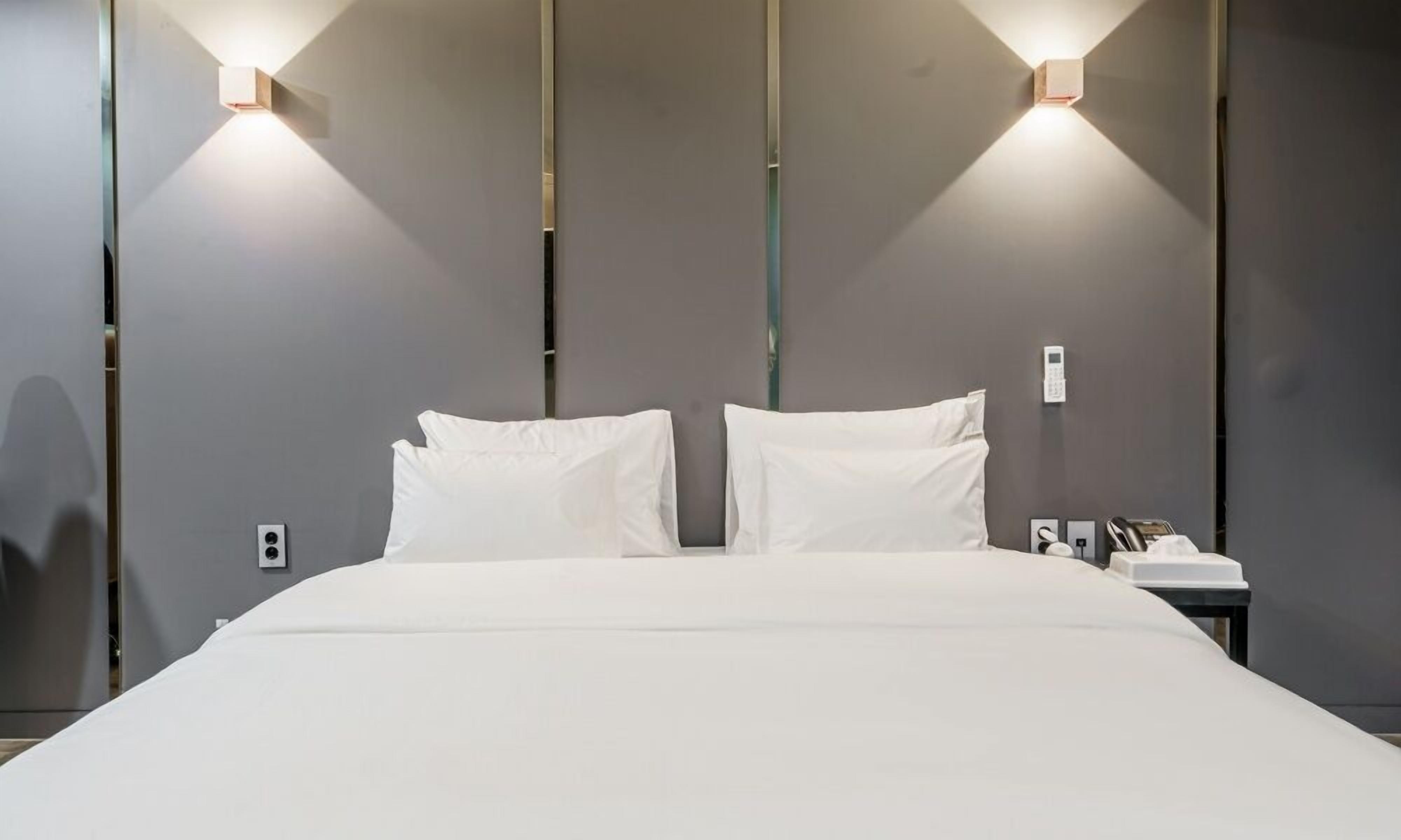A hotel room with a large bed, two bedside tables, and wall-mounted lighting.