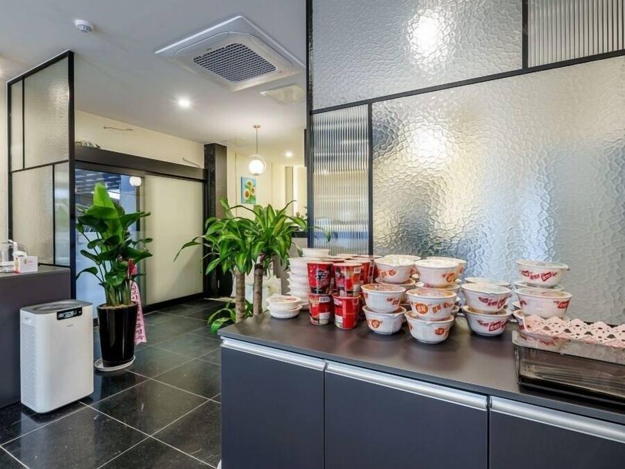 A hotel reception area with a counter, a trash bin, and a stack of bowls on the counter.