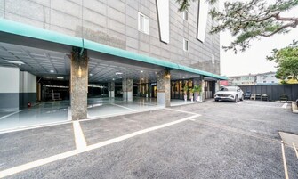 A modern building with a covered entrance, a parking area, and a white car parked outside.