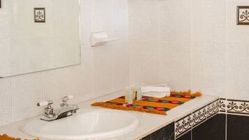 A bathroom with a white sink, a mirror, and a towel rack.