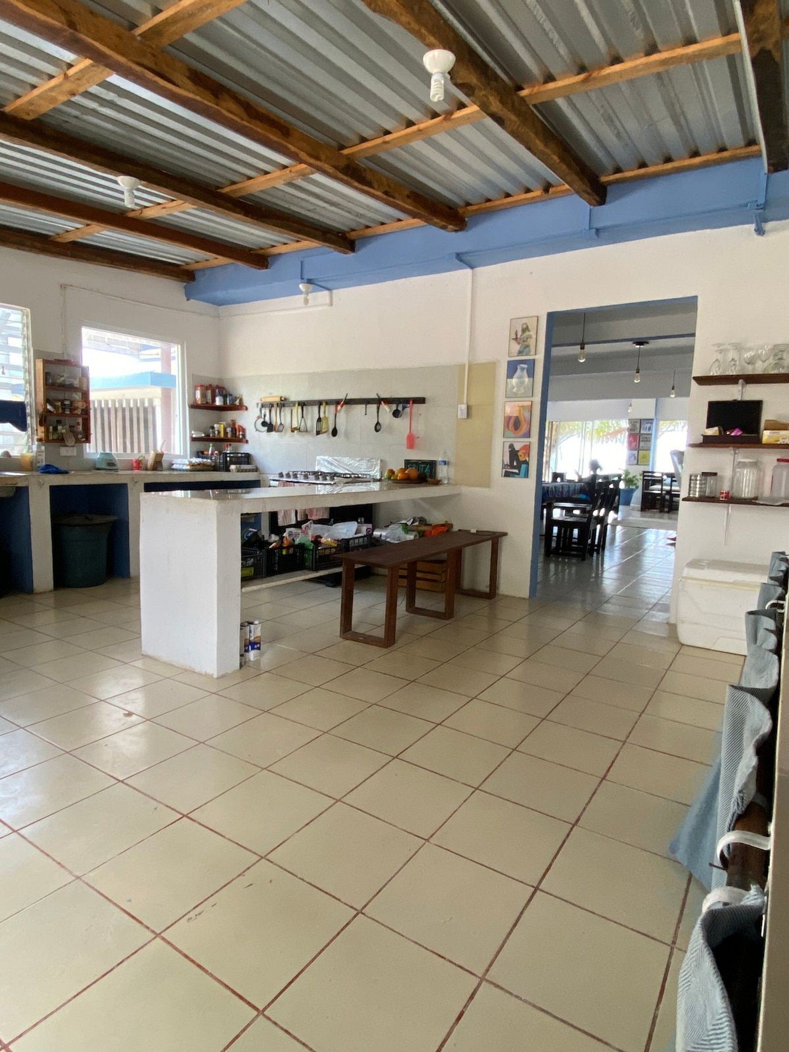 Una cocina amplia con una isla central, un comedor con sillas y piso de baldosas.