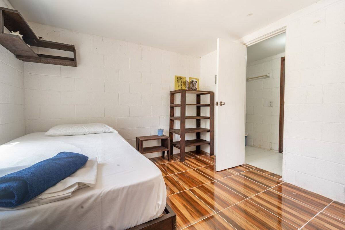 Una habitación con una cama, una estantería de madera y una puerta que da a un baño.