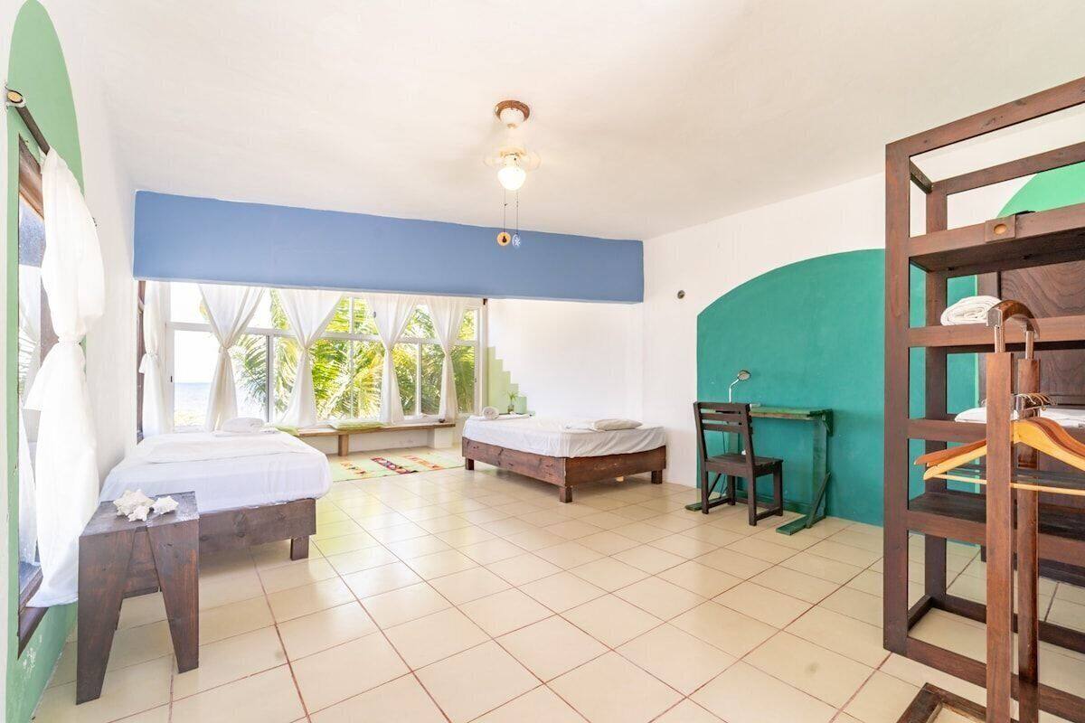 Una habitación con dos camas, un escritorio de madera y vistas al exterior.