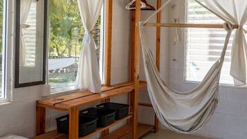 Una habitación con una hamaca, estanterías de madera, un colchón y un espejo.