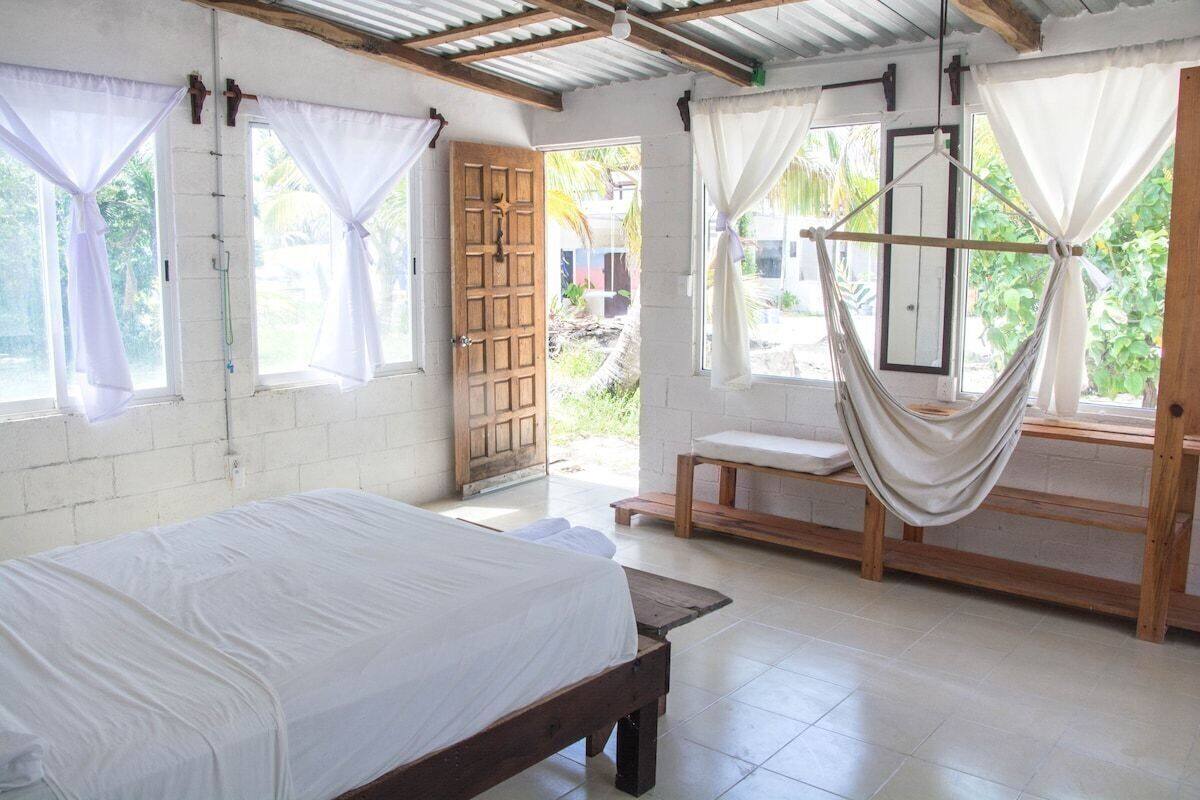 Una habitación con cama, banca y hamaca.