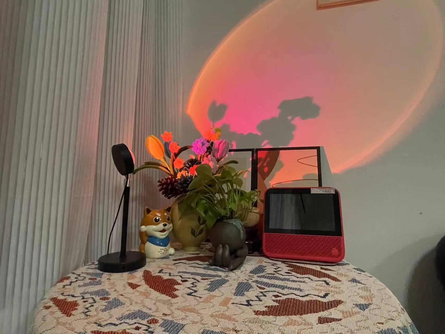 A table with a microphone, a ceramic fox figurine, a plant, and a red speaker.