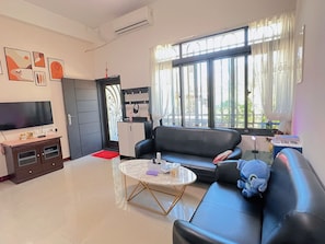 Relax in this stylish living room with a comfortable sofa, flat-screen TV, and ample natural light.