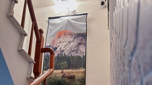 Una escalera con barandilla de madera, un cartel con un paisaje de montaña y un perro sentado en los escalones.