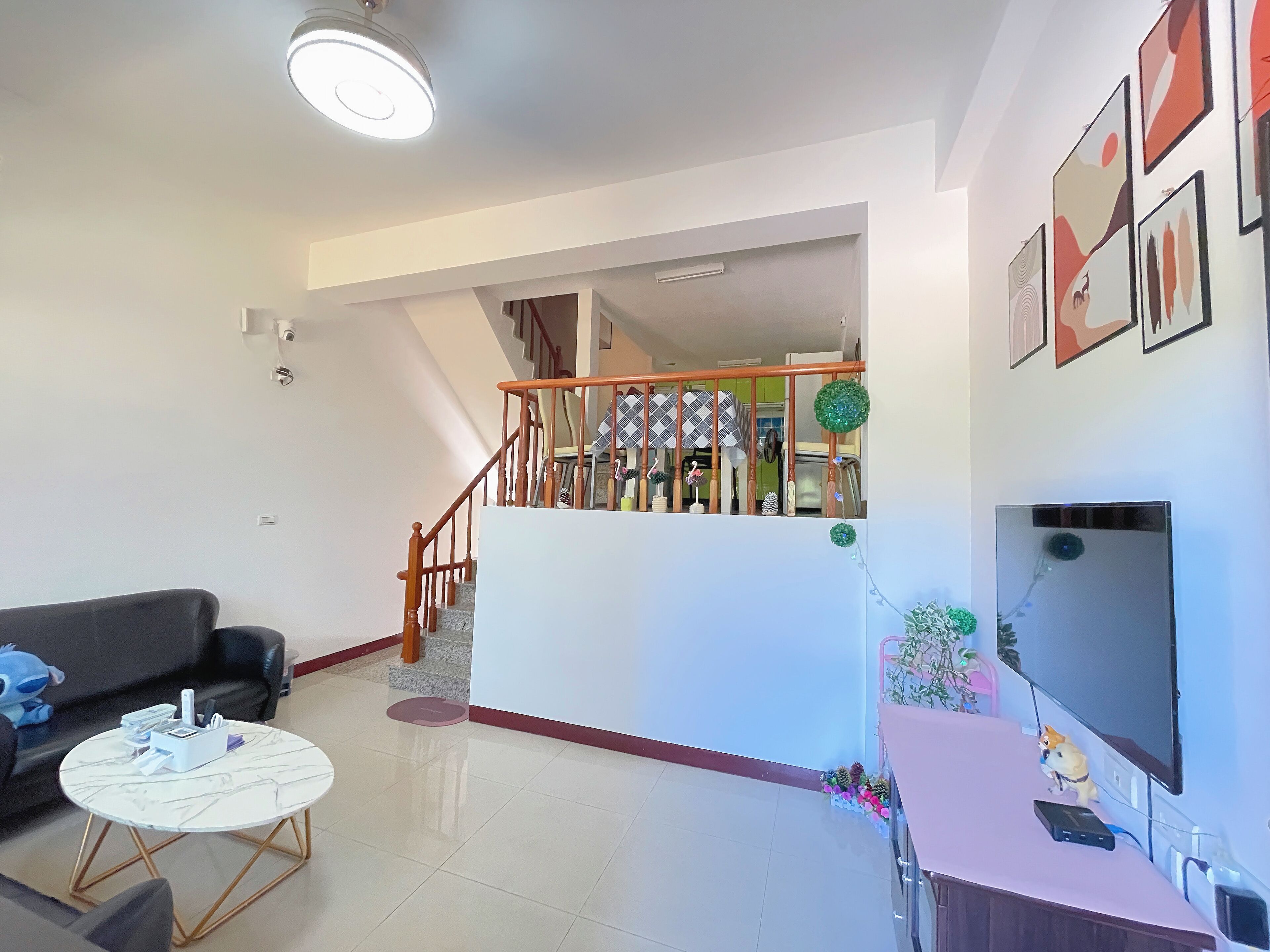 A living room with a sofa, coffee table, TV, and a staircase leading to an upper level.