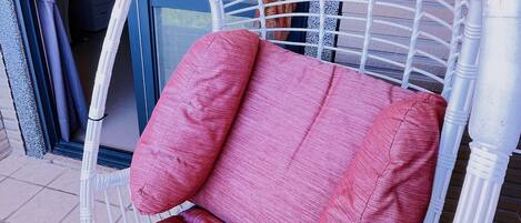 Una silla de mimbre blanca con cojines rojos.