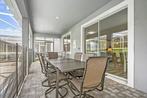 Enjoy meals al fresco at this outdoor dining area with a long table and six chairs, surrounded by a glass railing and offering a view of the surrounding landscape.