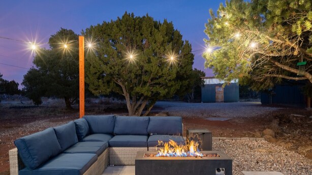 Un sofá modular con chimenea integrada, una chimenea de piedra y un árbol al fondo.