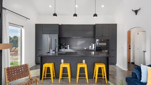 Una cocina moderna con una isla central, taburetes de bar e iluminación colgante.