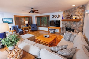 A living room with a sofa, coffee table, TV, fireplace, and wooden floors.