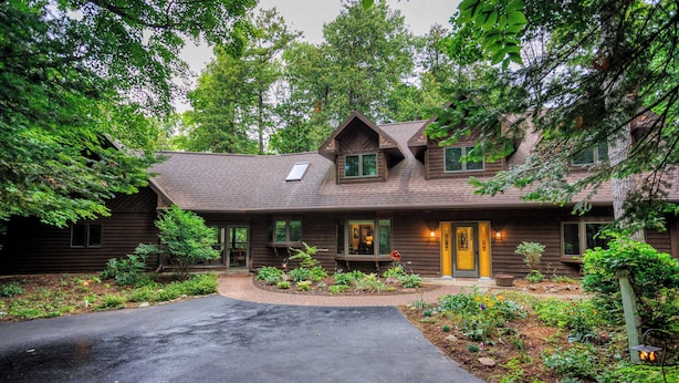 A wooden house with a sloped roof, a front porch, and a well-maintained garden.