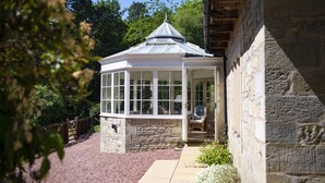 Ein Wintergarten mit Steinunterbau, großen Fenstern und einer Glasveranda.