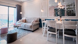 A modern living room with a sofa, ottoman, dining table, and chairs. - EEM Apartments Central (Ho Chi Minh City)