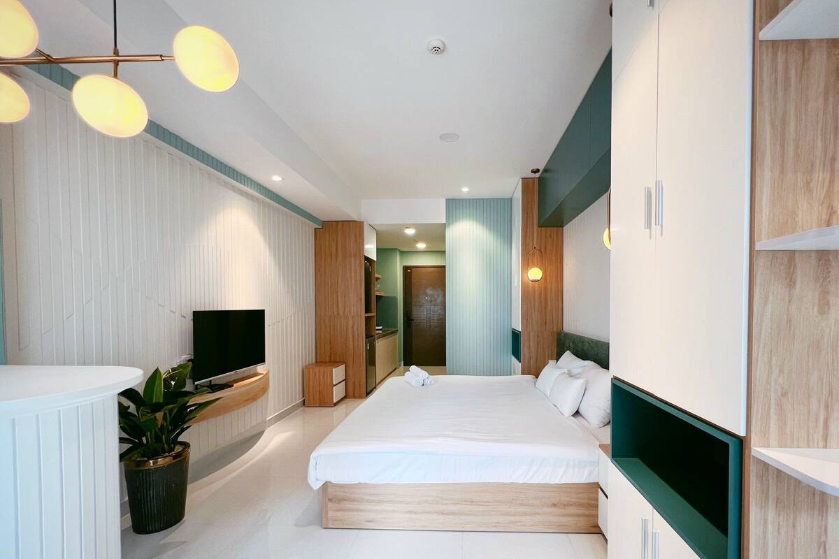 Een moderne hotelkamer met een groot bed, een ingebouwde televisie en een potplant.