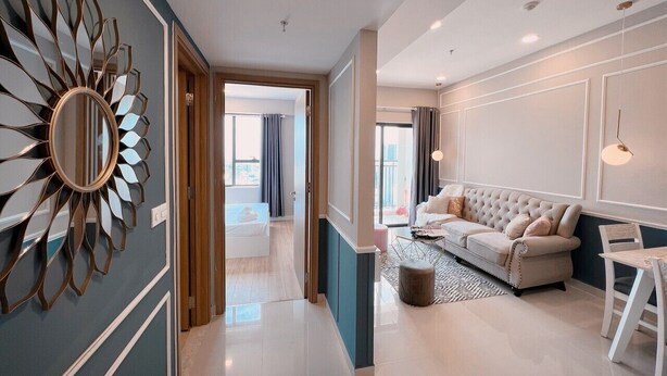 A modern living room with a sofa, a coffee table, and a decorative mirror. - EEM Apartments Central (Ho Chi Minh City)