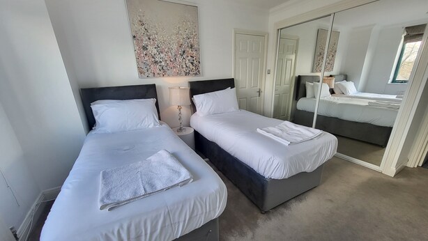 A hotel room with two beds, a large mirror, and a painting on the wall. - Garland Two Bedroom Apartment 1Min Walk to Station (London)