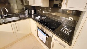 A modern kitchen with a stainless steel sink, a stove, and white cabinets. - Garland Two Bedroom Apartment 1Min Walk to Station (London)