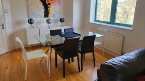 A modern office space with a glass table, black chairs, a white desk, and a colorful abstract painting on the wall. - Garland Two Bedroom Apartment 1Min Walk to Station (London)