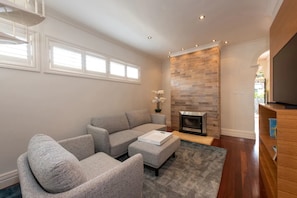 A modern living room with a grey sectional sofa, a fireplace, and a flat-screen TV.