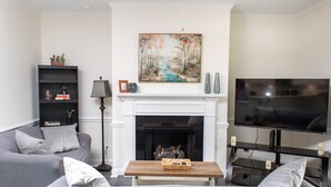 Una sala de estar moderna con chimenea, televisor de pantalla plana, sofá y estantería.