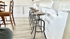 Una cocina con suelo de madera, paredes blancas y una zona de bar con taburetes.