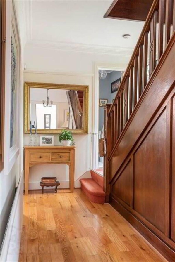 A wooden staircase leading to a landing with a mirror above a wooden desk. - Delightful Family Home (Lisburn)