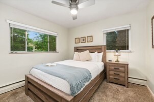 A bedroom with a bed, bedside tables, a ceiling fan, and windows.