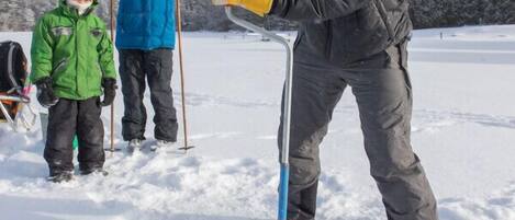 Una persona usando una herramienta metálica en la nieve.
