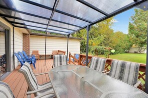 Eine überdachte Sitzgelegenheit auf einer Terrasse mit Tisch und Stühlen.