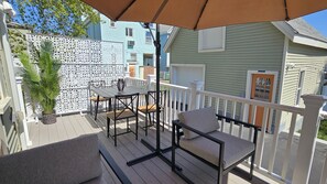 A wooden deck with outdoor furniture, a white fence, and a house in the background.